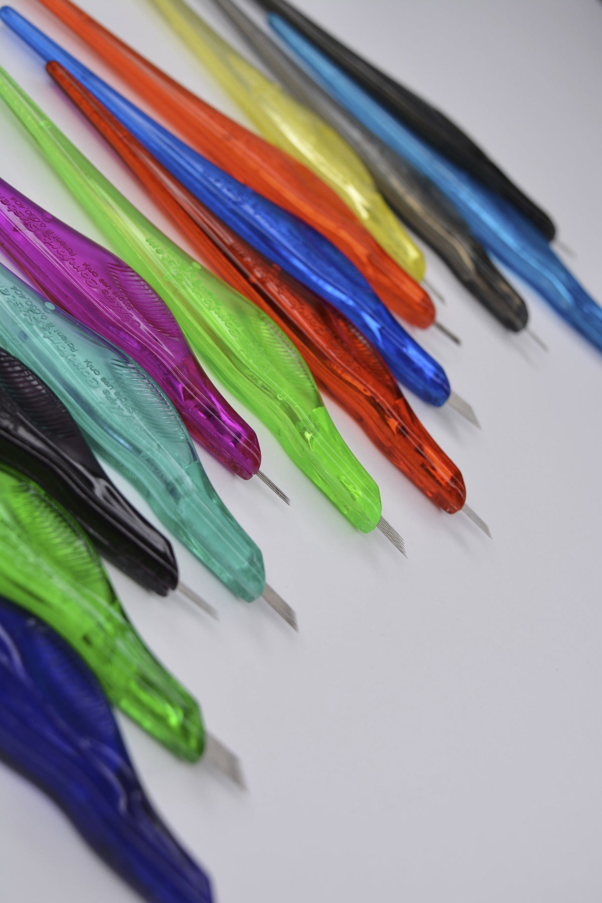 Colorful SofTap hand tool needles for PMU arranged on a white background