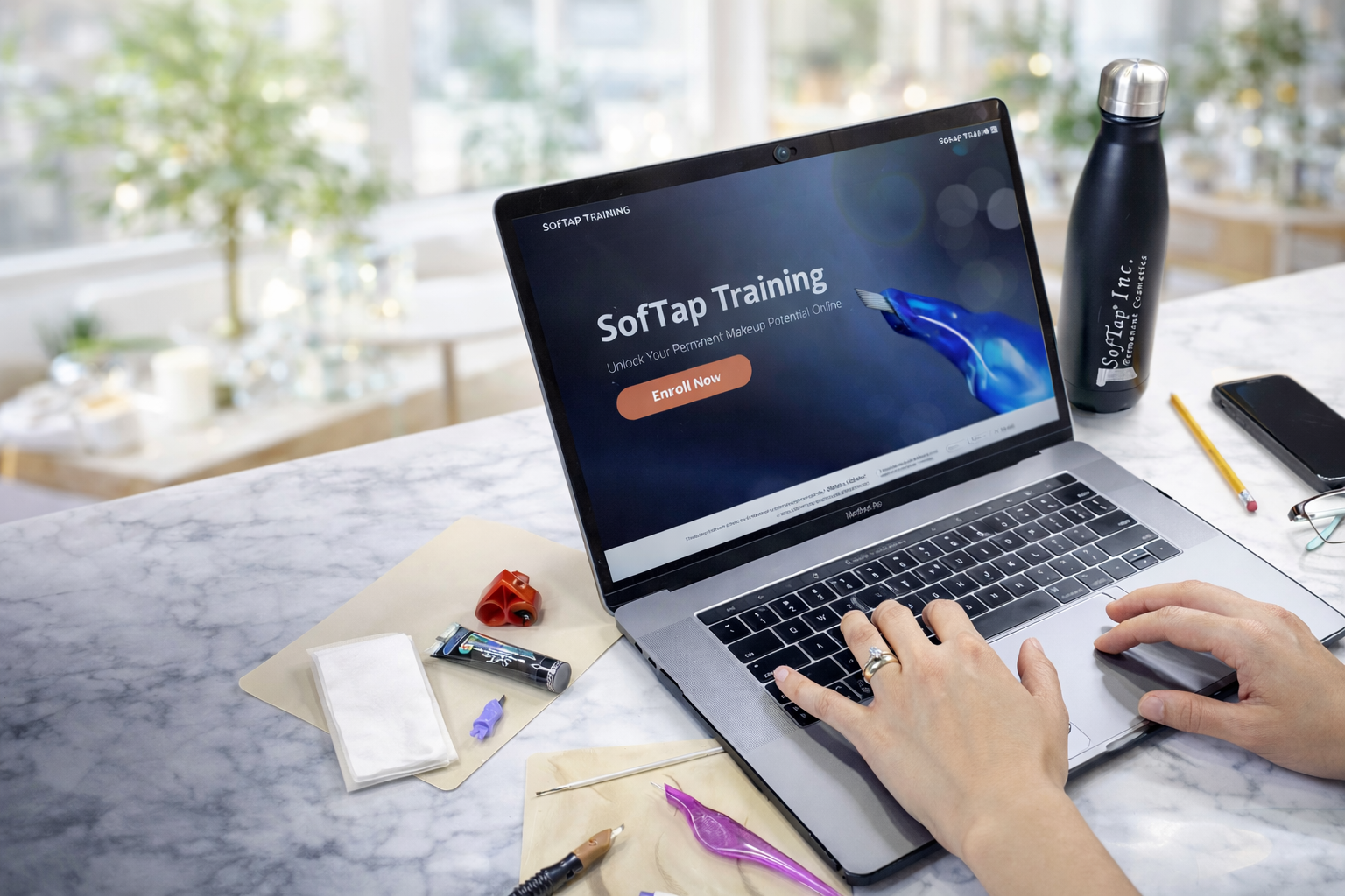 Person using a laptop with 'Softap Training' on the screen at a desk.