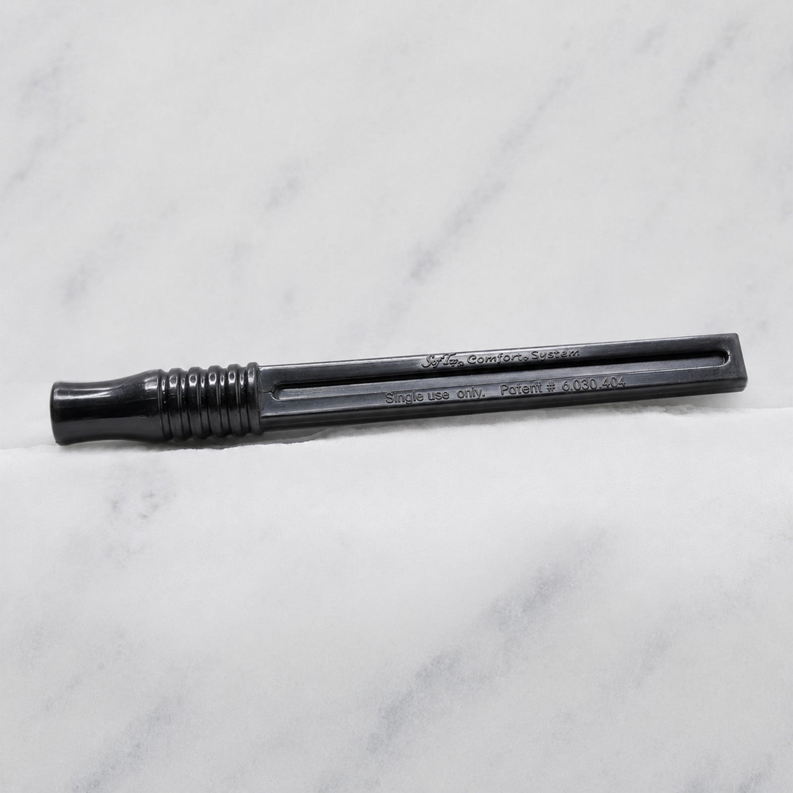 A close-up of SofTap pmu click stick handle, resting on a white marble surface.