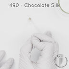 white gloved hand with white brush smearing SofTap dark brown Chocolate Silk Color for permanent eyebrows