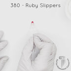 white gloved hand with white brush smearing SofTap Red Ruby Slippers Color for permanent lips