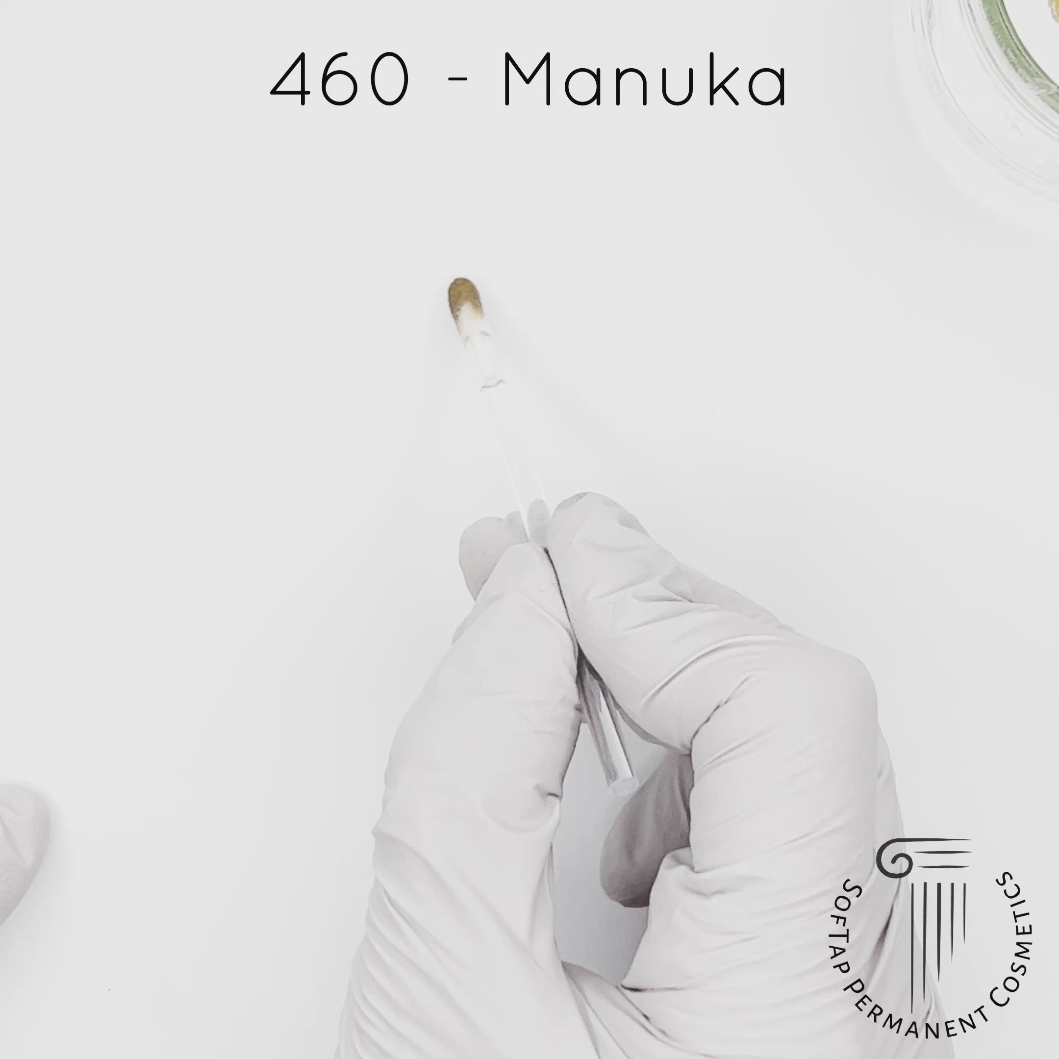 white gloved hand with white brush smearing SofTap medium blonde Manuka Color for permanent eyebrows