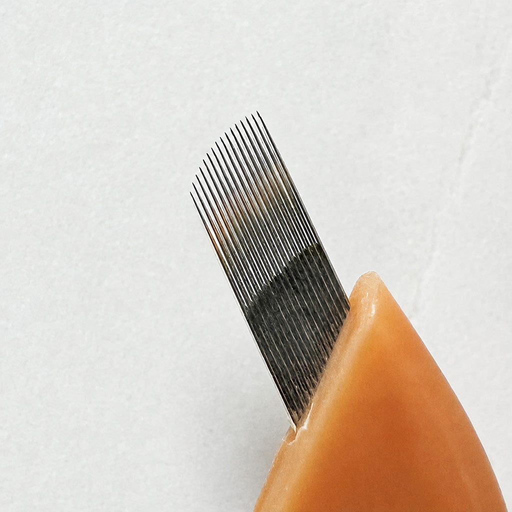 Close-up of SofTap permanent makeup 16 curve fine gauge needle shown against a light textured background.