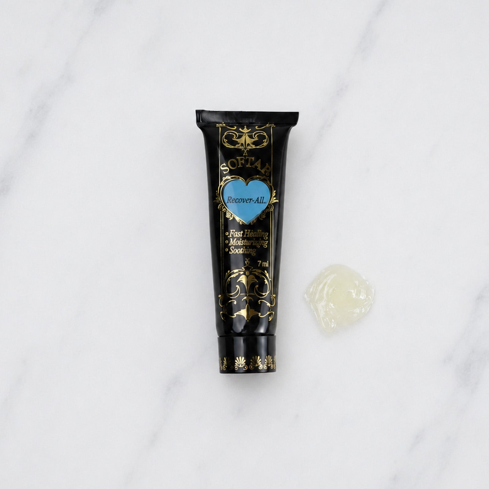 SofTap aftercare healing product Recoverall tube with blob of off-white oitment on white marble background