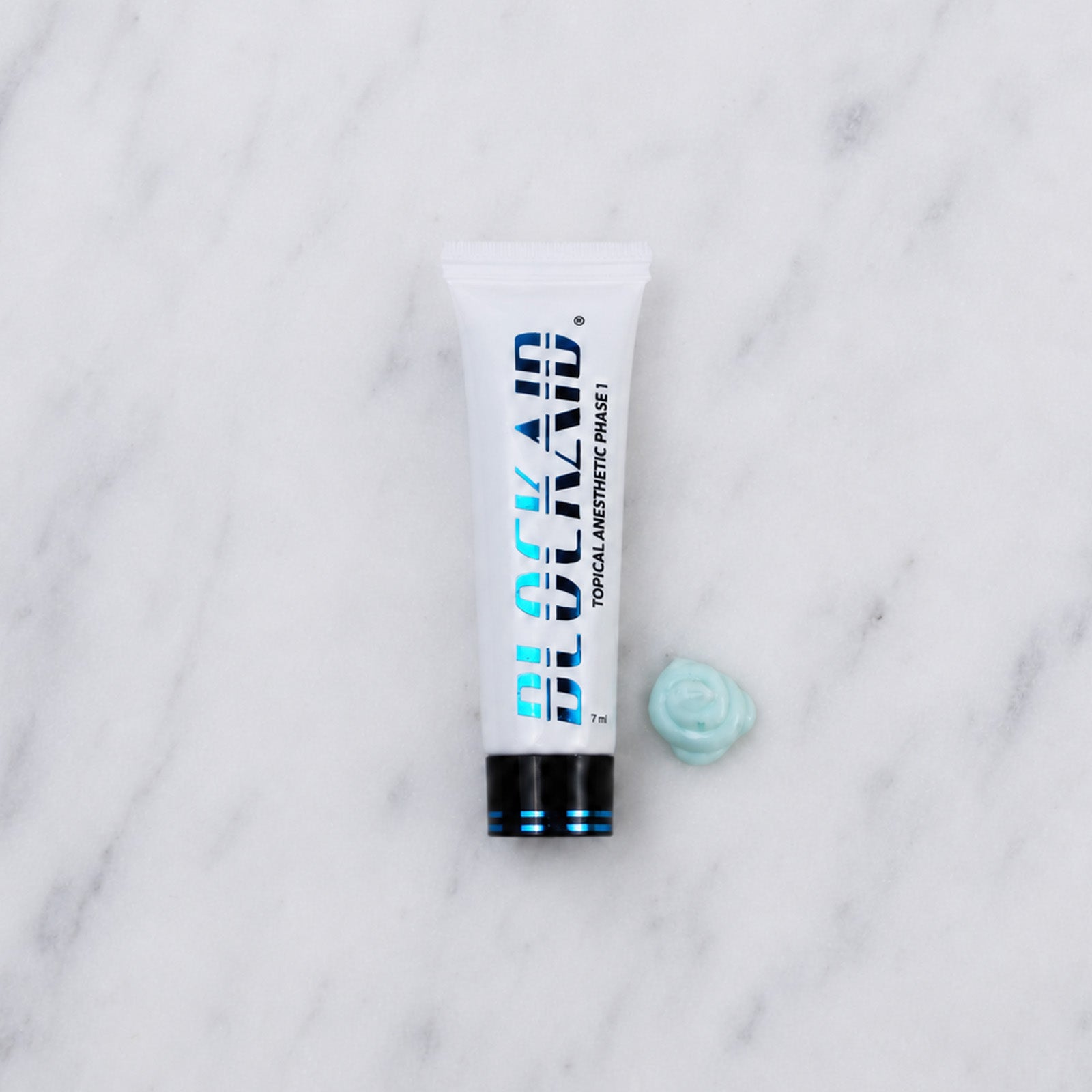 SofTap topical anesthetic Blockaid tube with blob of blue cream on white marble background