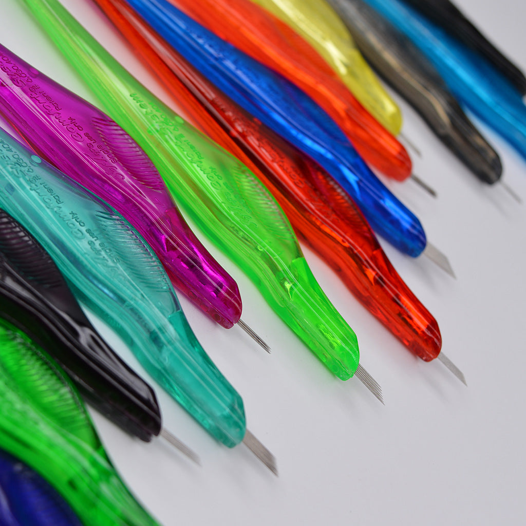 Close-up of several colorful SofTap permanent makeup disposable pen needles arranged diagonally on a light grey background.