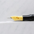 A close-up of SofTap 10 fine pmu needle click tip, resting on a white marble surface.