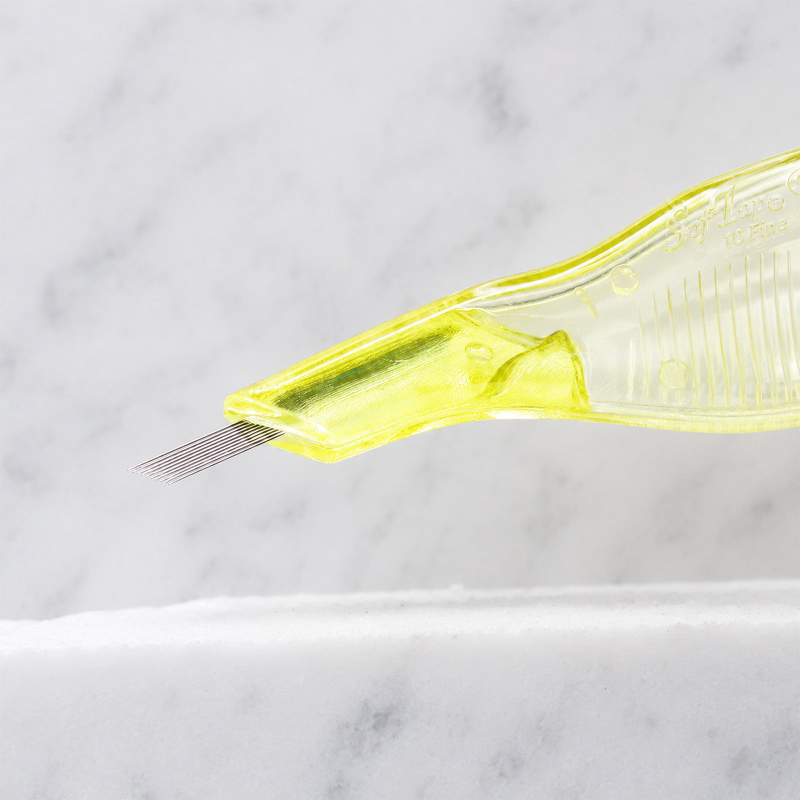 A close-up of SofTap 10 fine pmu needle disposable pen, resting on a white marble surface.