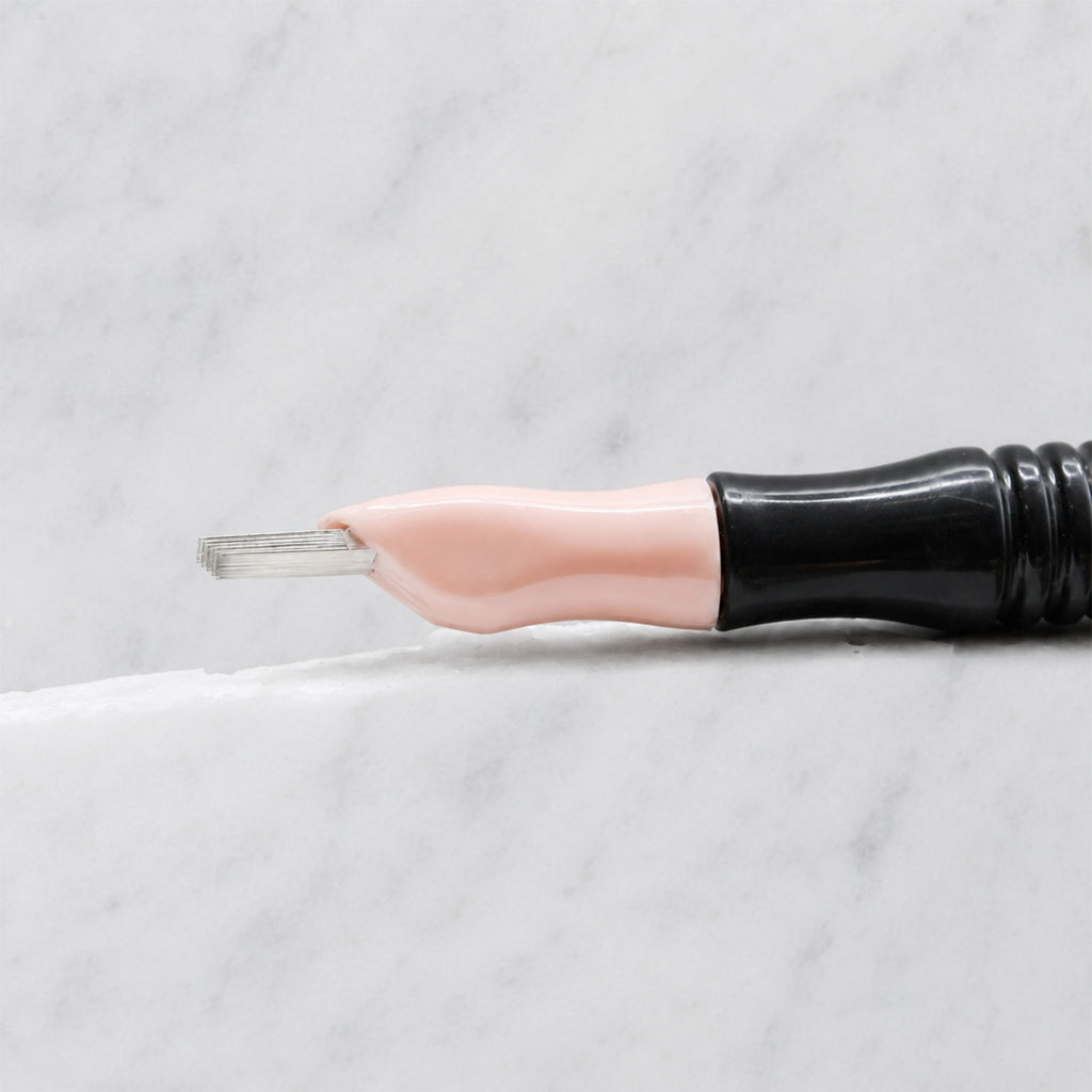 A close-up of SofTap 114 pmu needle click tip, resting on a white marble surface.