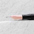 A close-up of SofTap 114 pmu needle click tip, resting on a white marble surface.