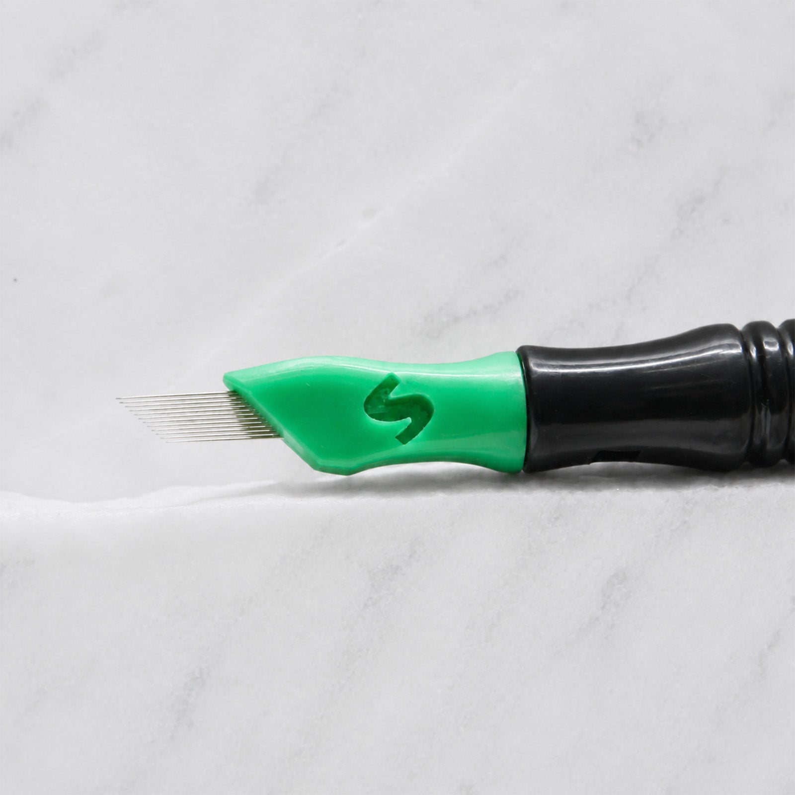 A close-up of SofTap 12 pmu needle click tip, resting on a white marble surface.