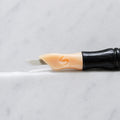 A close-up of SofTap 13 smudger pmu needle click tip, resting on a white marble surface.