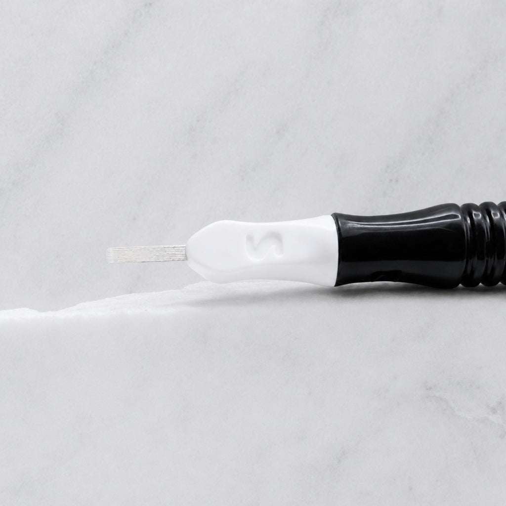 A close-up of SofTap 13 u nano pmu needle click tip, resting on a white marble surface.