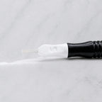 A close-up of SofTap 13 u nano pmu needle click tip, resting on a white marble surface.