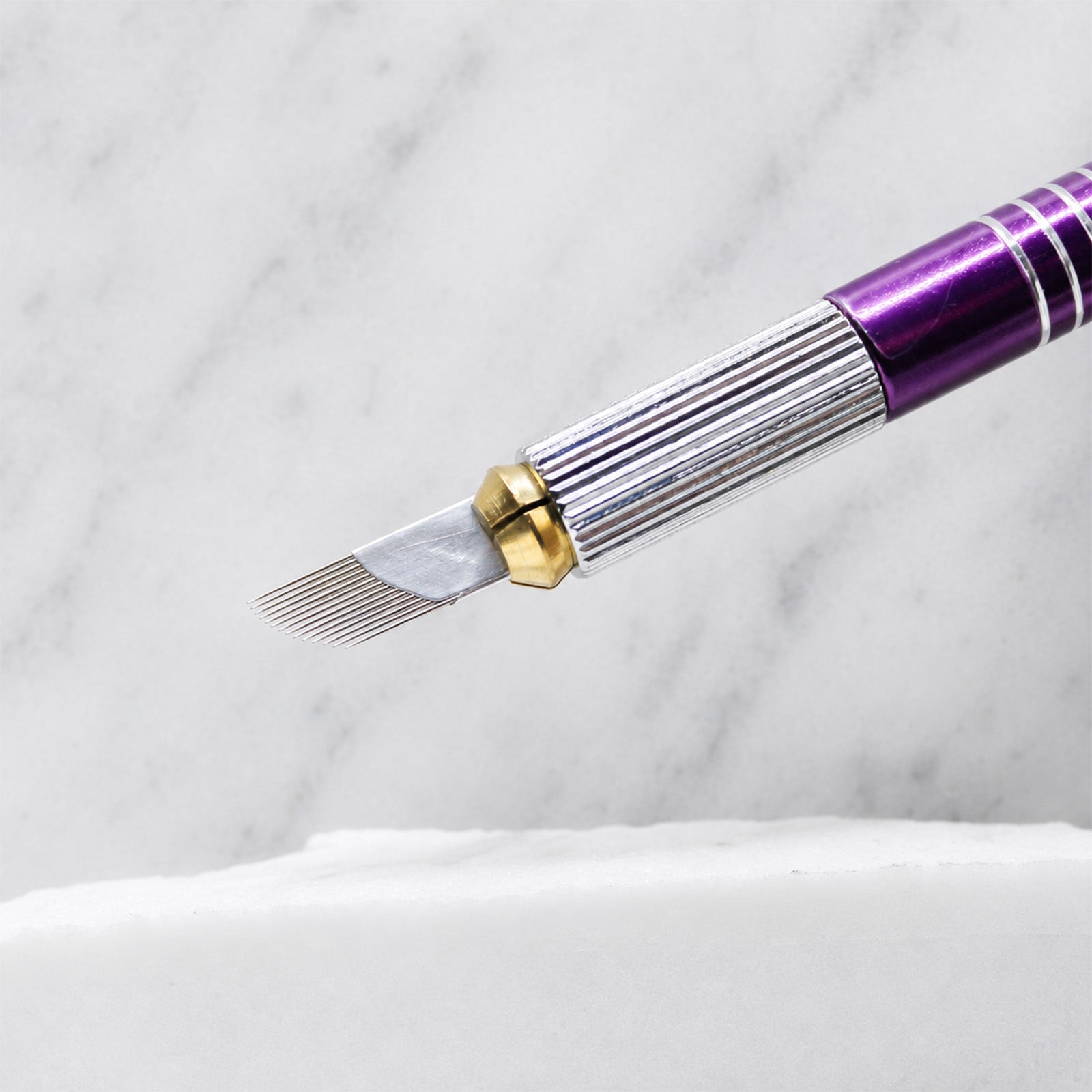 A close-up of SofTap 14 curve pmu needle foil cartridge, resting on a white marble surface.