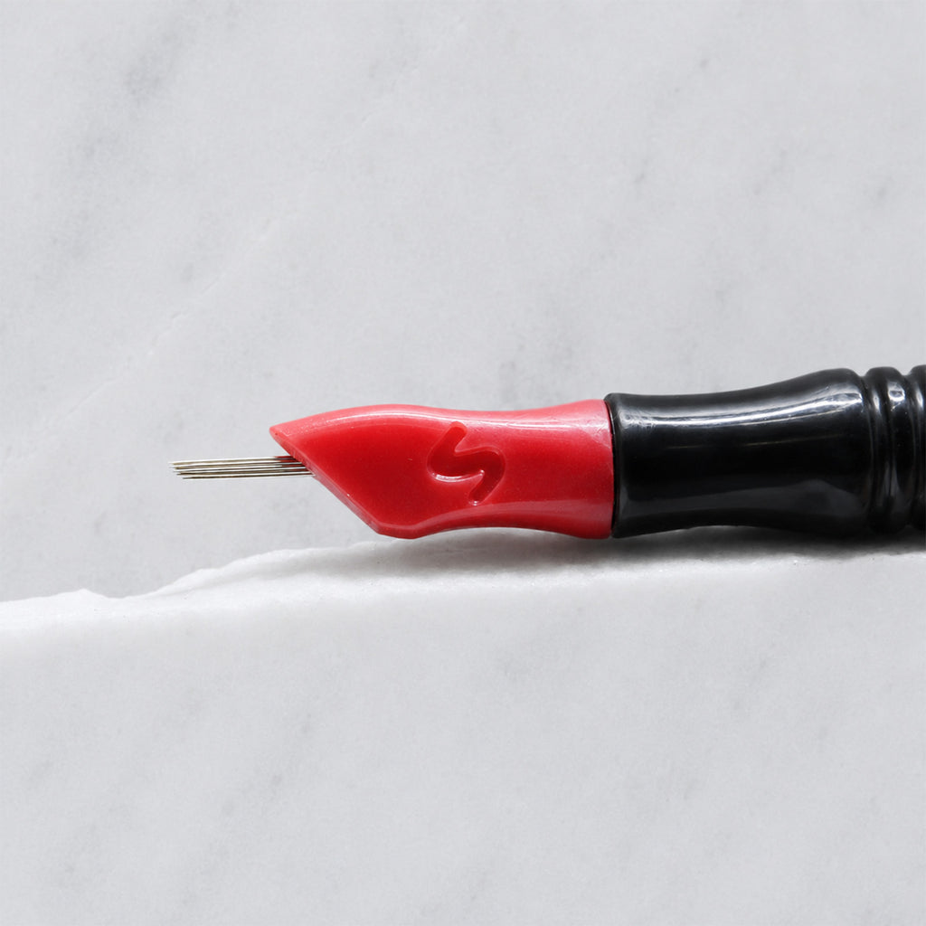 A close-up of SofTap 15 round pmu needle click tip, resting on a white marble surface.