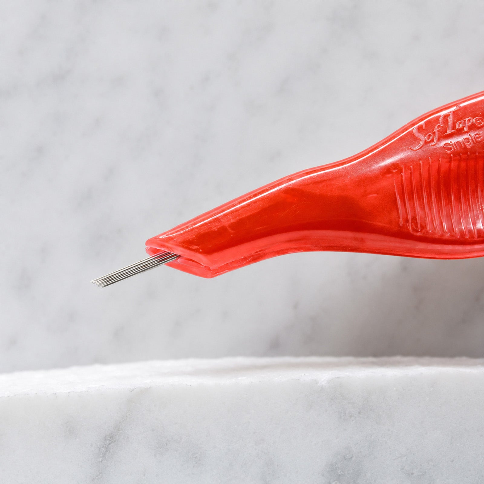A close-up of SofTap 15 round pmu needle disposable pen, resting on a white marble surface.