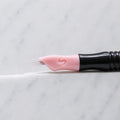 A close-up of SofTap 15 smudger pmu needle click tip, resting on a white marble surface.