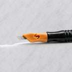 A close-up of SofTap 16 curve pmu needle click tip, resting on a white marble surface.