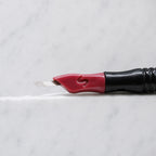 A close-up of SofTap 17 curve nano pmu needle click tip, resting on a white marble surface.