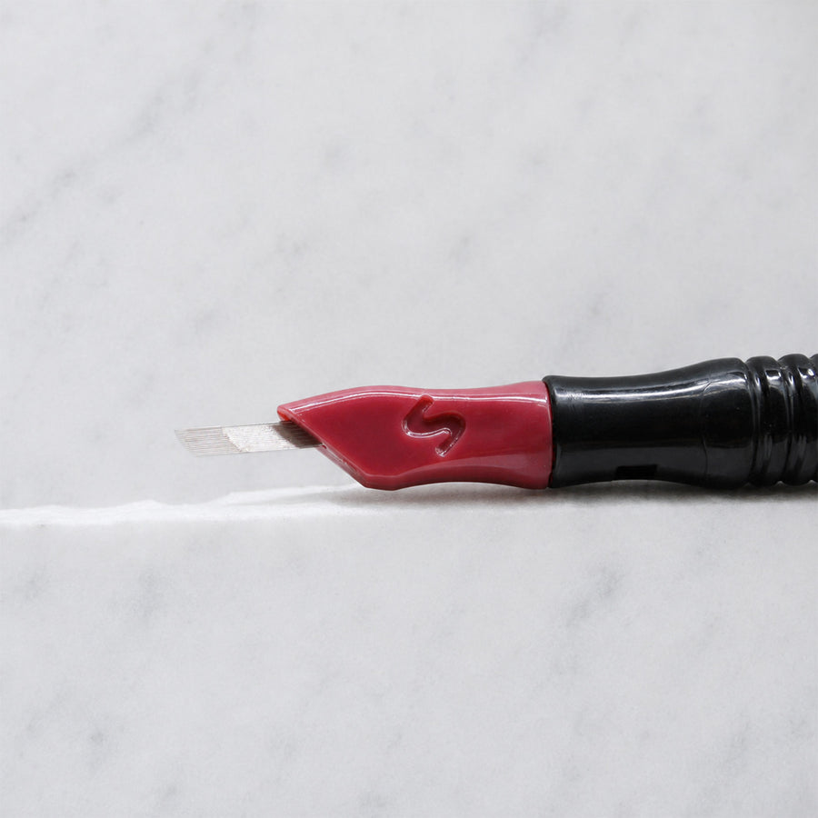 A close-up of SofTap 17 curve nano pmu needle click tip, resting on a white marble surface.