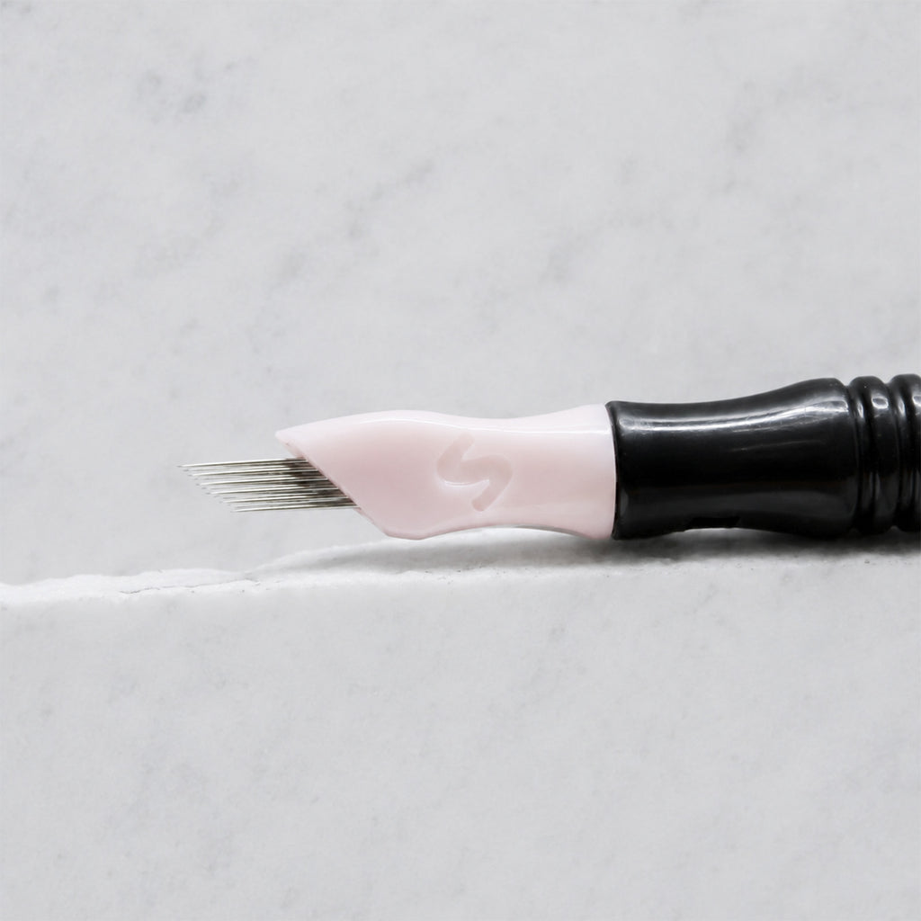A close-up of SofTap 17 ultimate pmu needle click tip, resting on a white marble surface.