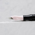A close-up of SofTap 17 ultimate pmu needle click tip, resting on a white marble surface.