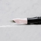 A close-up of SofTap 17 ultimate pmu needle click tip, resting on a white marble surface.