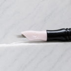 A close-up of SofTap 20 ultimate smudger pmu needle click tip, resting on a white marble surface.