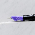 A close-up of SofTap 23 smudger pmu needle click tip, resting on a white marble surface.