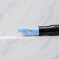 A close-up of SofTap 24 fine pmu needle click tip, resting on a white marble surface.