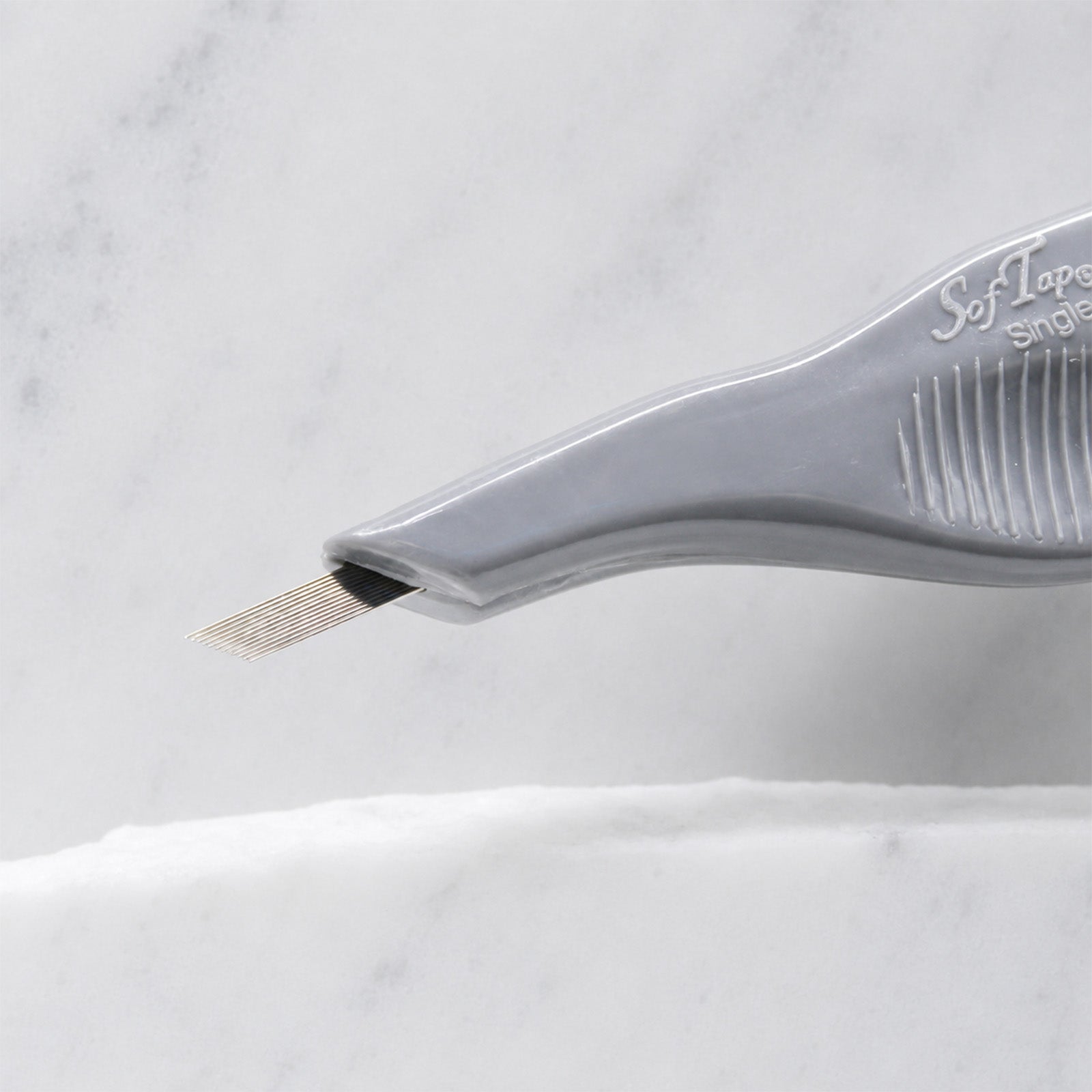 A close-up of SofTap 24 fine pmu needle disposable pen, resting on a white marble surface.
