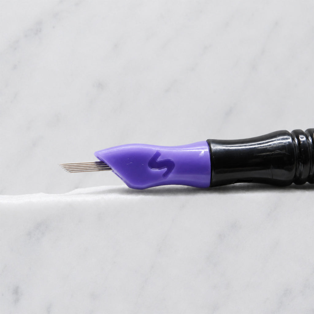 A close-up of SofTap 25 round pmu needle click tip, resting on a white marble surface.