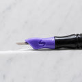 A close-up of SofTap 25 round pmu needle click tip, resting on a white marble surface.