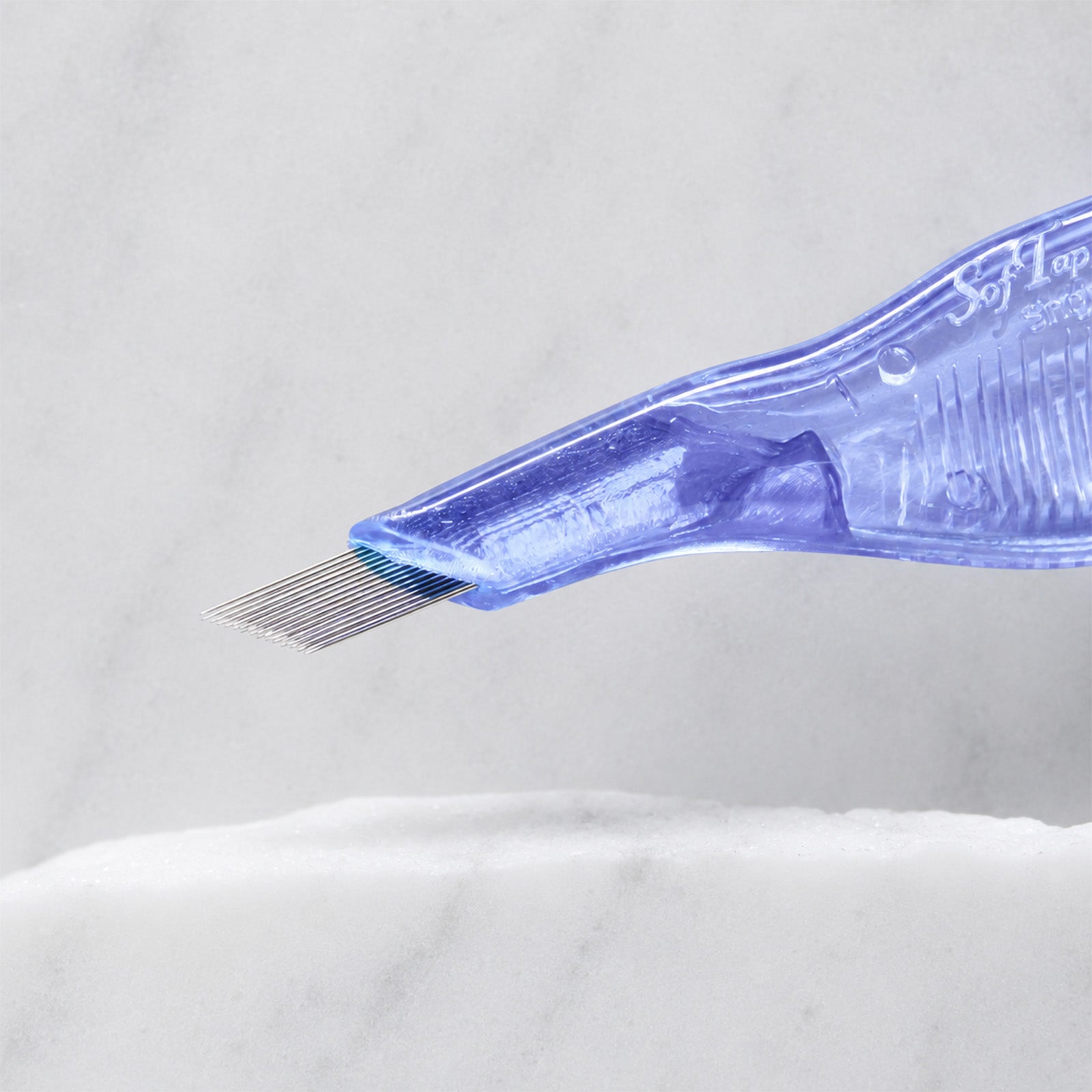 A close-up of SofTap 28 pmu needle disposable pen, resting on a white marble surface.
