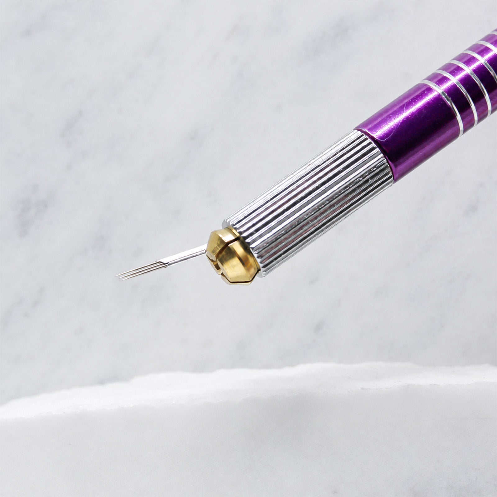 A close-up of SofTap 3 pmu needle foil cartridge, resting on a white marble surface.