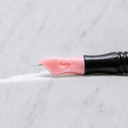 A close-up of SofTap 3 round pmu needle click tip, resting on a white marble surface.