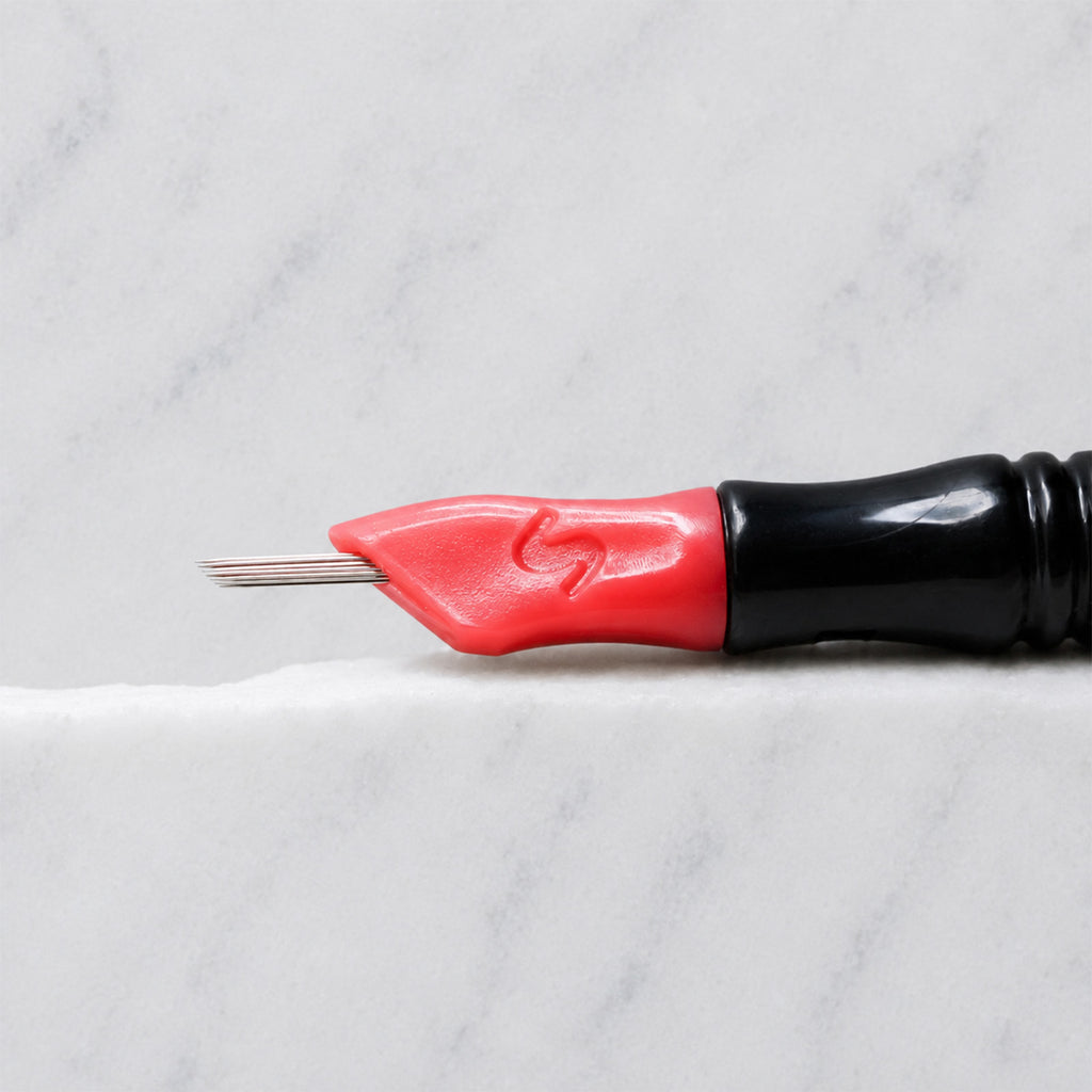 A close-up of SofTap 33 round pmu needle click tip, resting on a white marble surface.