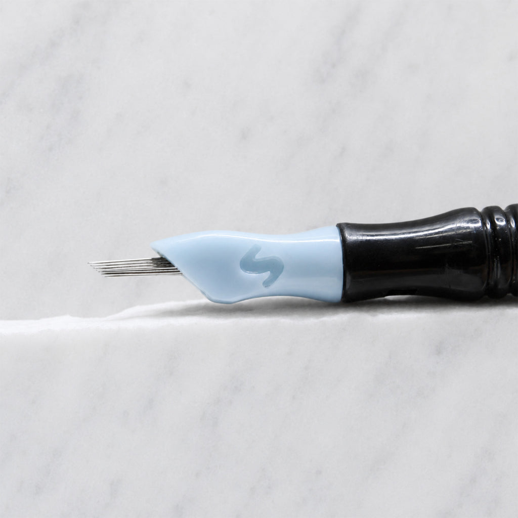 A close-up of SofTap 36 round pmu needle click tip, resting on a white marble surface.
