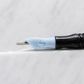A close-up of SofTap 36 round pmu needle click tip, resting on a white marble surface.