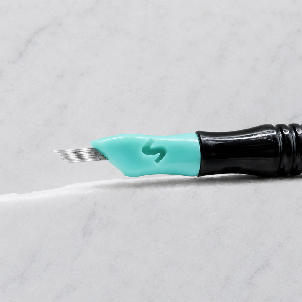 A close-up of SofTap 39 pmu needle click tip, resting on a white marble surface.
