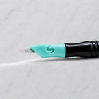 A close-up of SofTap 39 pmu needle click tip, resting on a white marble surface.