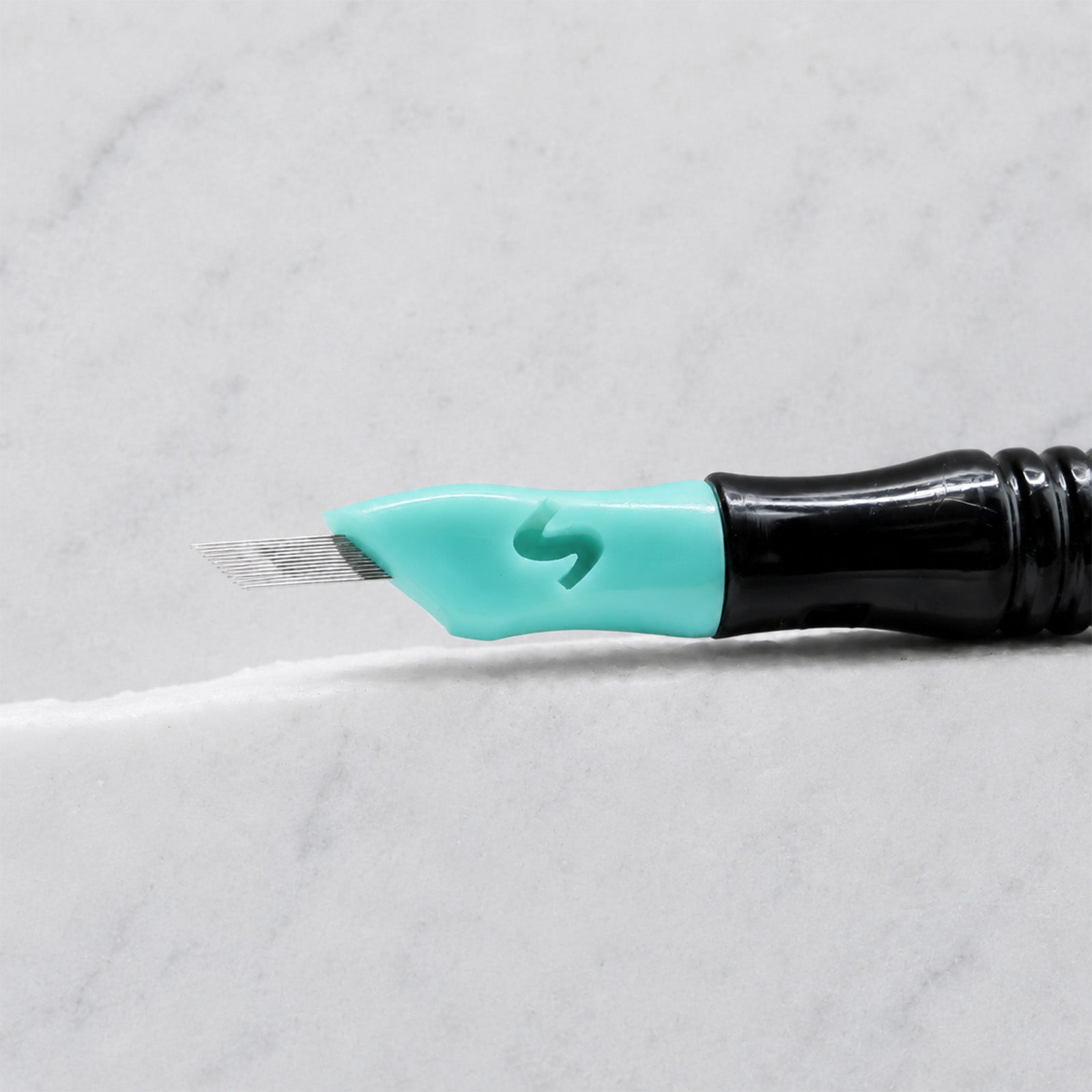 A close-up of SofTap 39 pmu needle click tip, resting on a white marble surface.