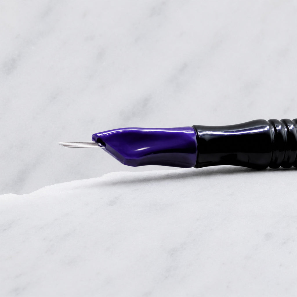 A close-up of SofTap 5 pmu needle click tip, resting on a white marble surface.