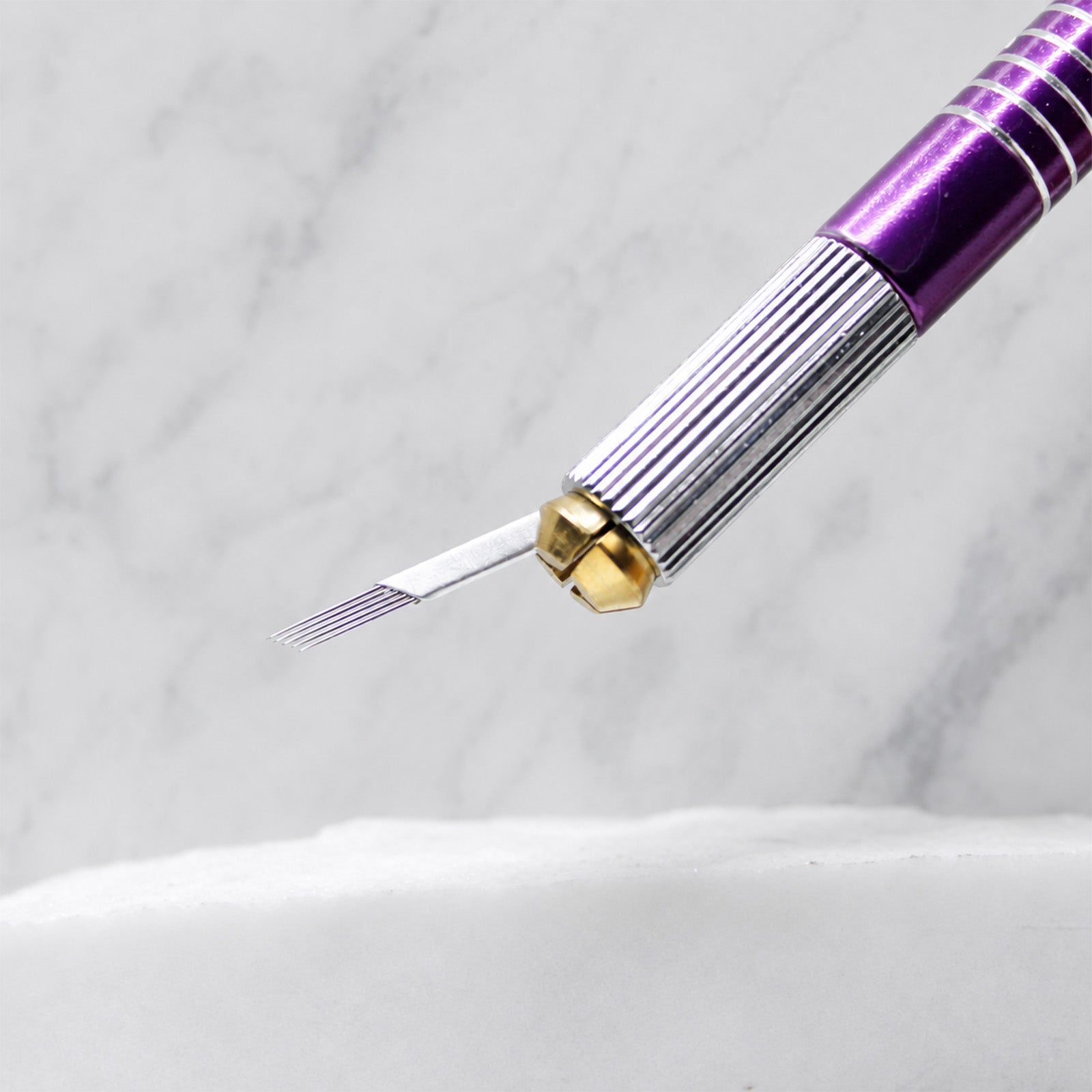 A close-up of SofTap 5 pmu needle foil cartridge, resting on a white marble surface.