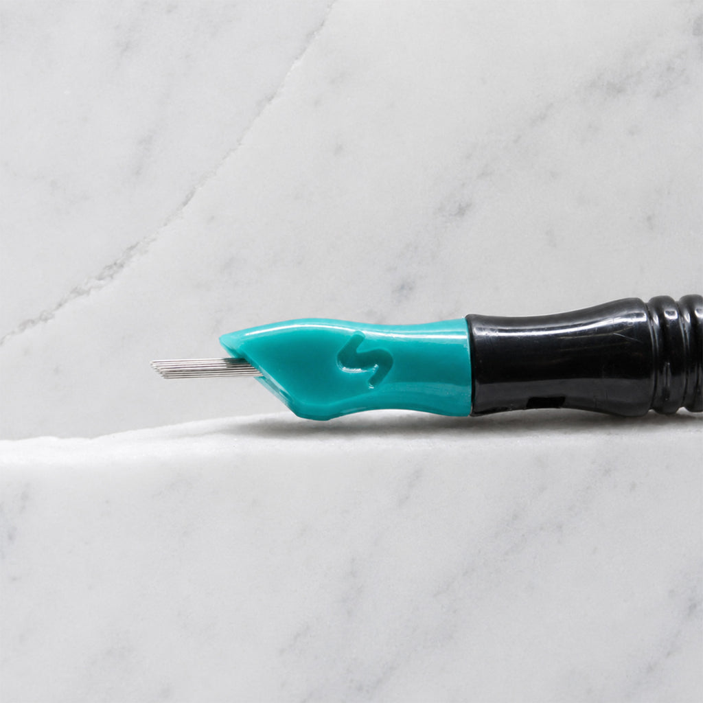 A close-up of SofTap 52 round pmu needle click tip, resting on a white marble surface.