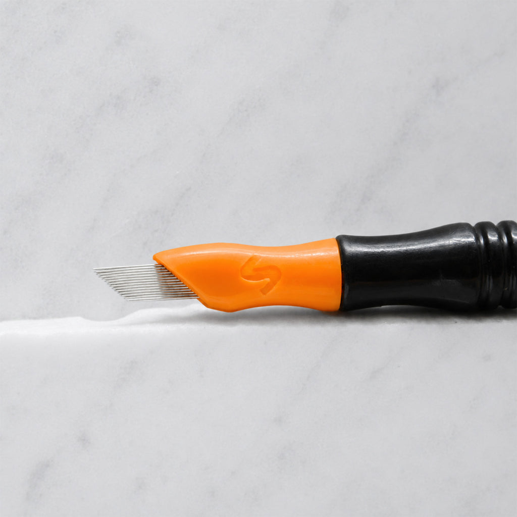 A close-up of SofTap 56 pmu needle click tip, resting on a white marble surface.