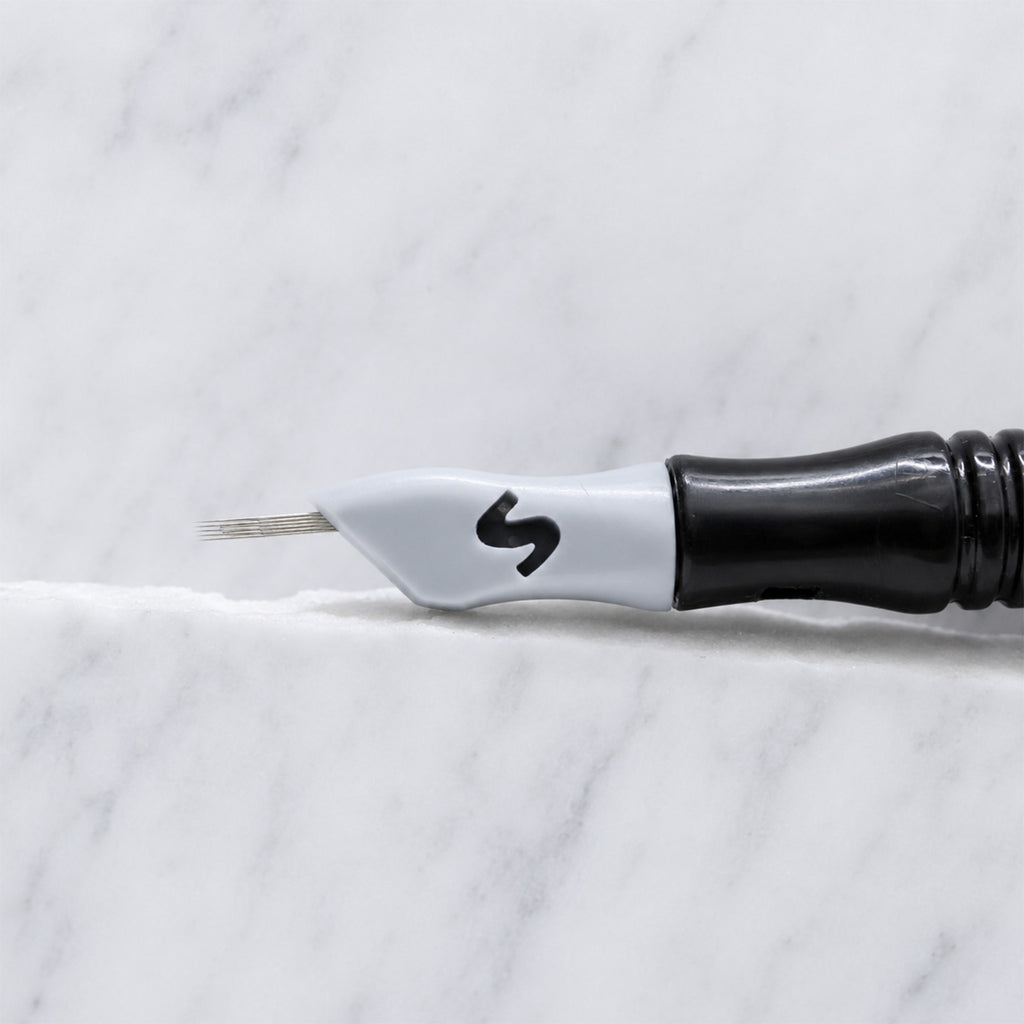 A close-up of SofTap 6 fine curve pmu needle click tip, resting on a white marble surface.