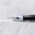 A close-up of SofTap 6 fine curve pmu needle click tip, resting on a white marble surface.