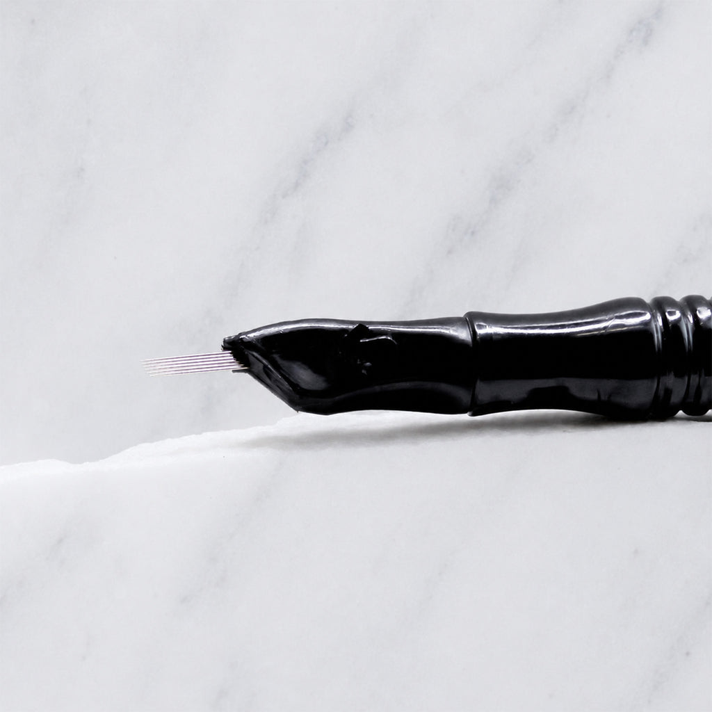 A close-up of SofTap 6 reg curve pmu needle click tip, resting on a white marble surface.